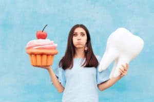 Woman holding big cupcake and tooth on blue background.
