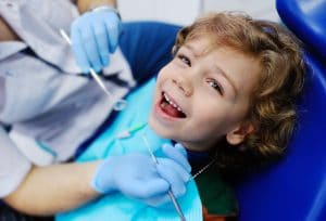 cute child with curly hair in a dental chair smiling