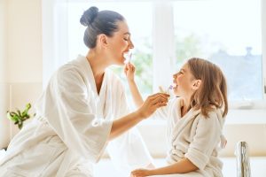 Happy family! Mother and daughter child girl are brushing teeth toothbrushes in the bathroom.