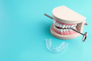 Artificial jaw, dental mirror and occlusal splint on color background