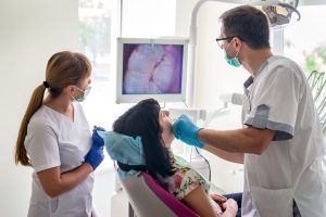 Doctor examining patient's teeth with intraoral camera